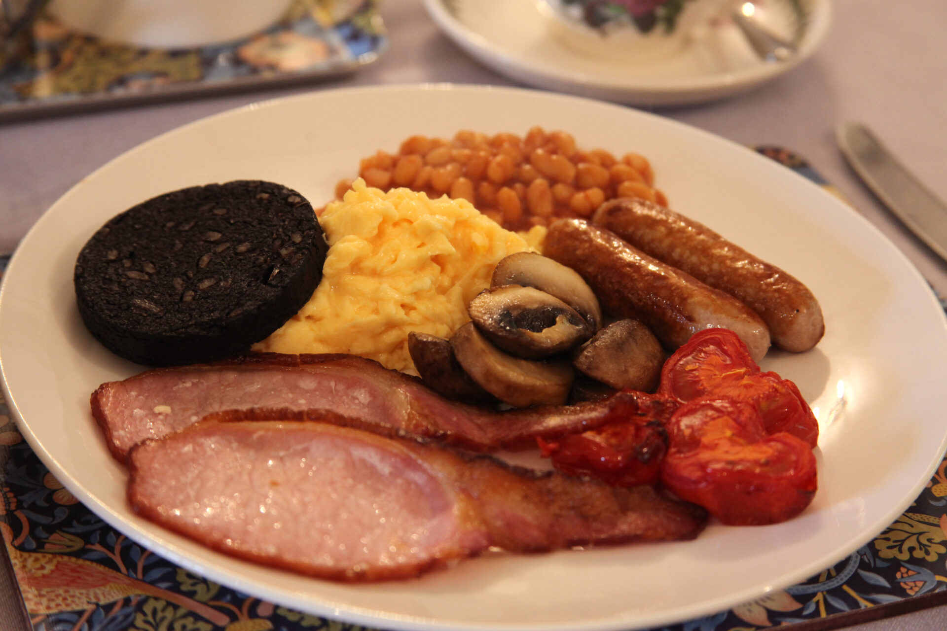 Full English breakfast plate with sausages, bacon, eggs and beans