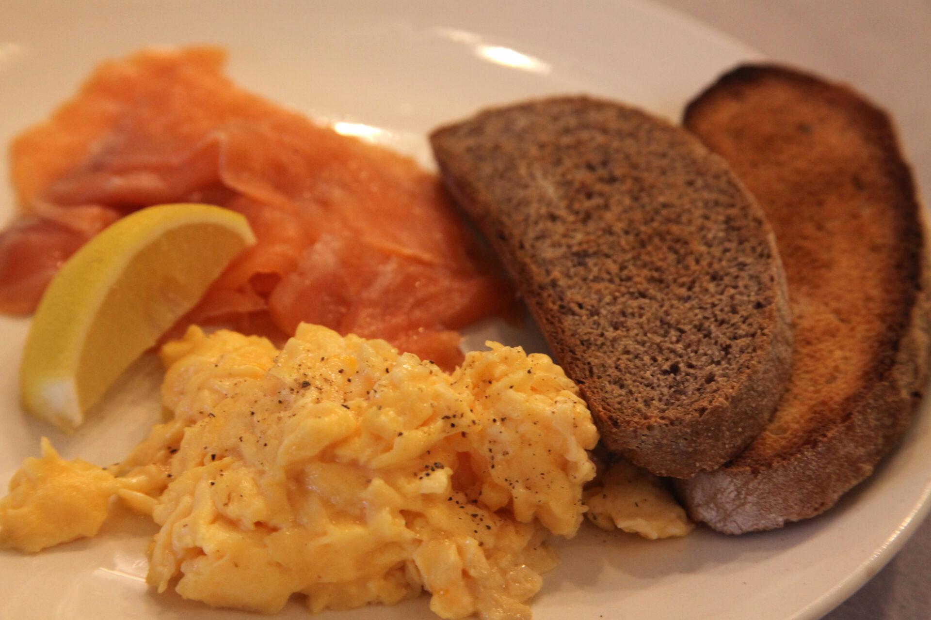 Scrambled eggs with smoked salmon, toast and lemon wedge